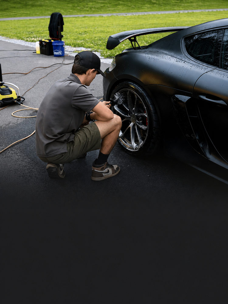 Detailer cleaning a sports car wheel during a full detail in Knoxville